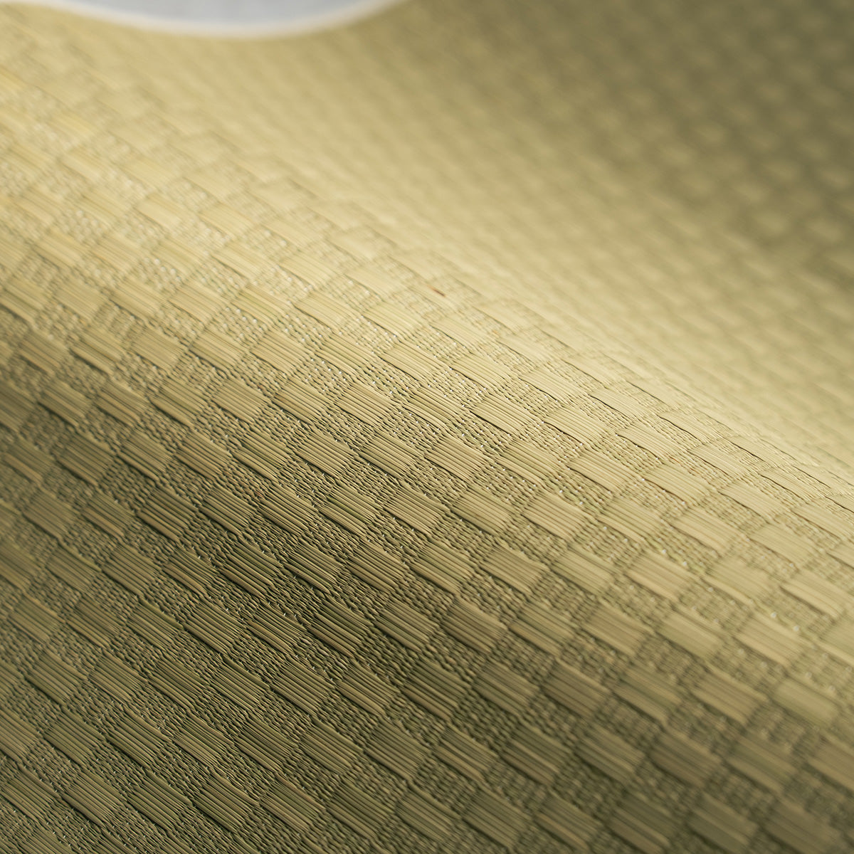 A natural undyed igusa tatami yoga mat unrolled on a wood floor.