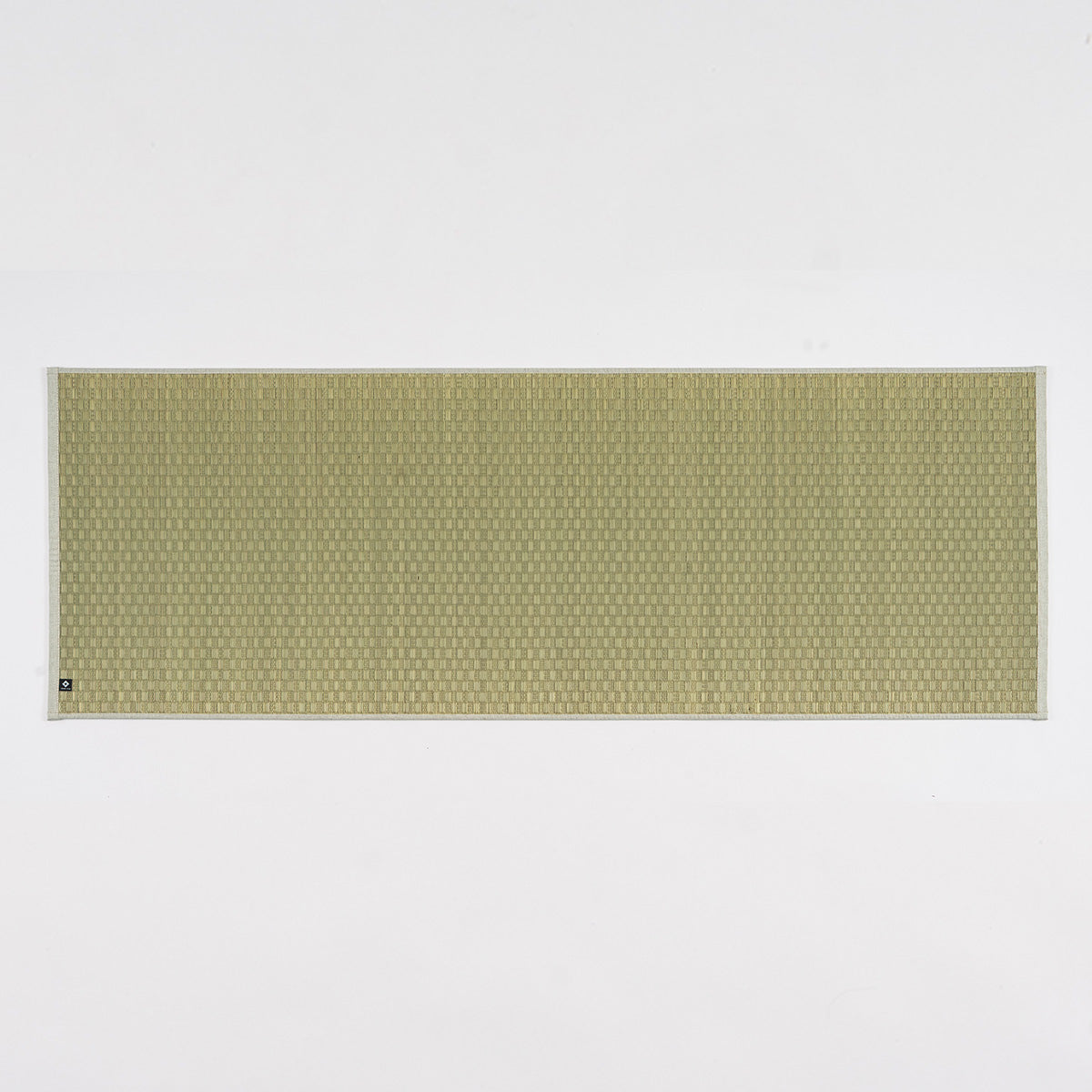 A natural undyed igusa tatami yoga mat unrolled on a wood floor.