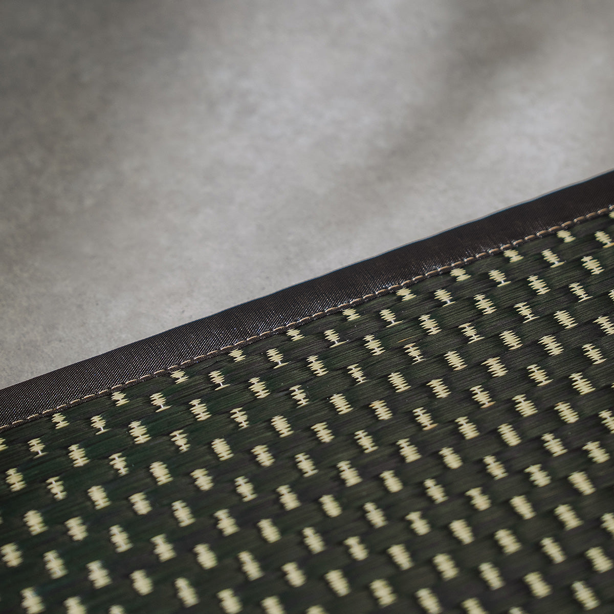 A folded three-fold black igusa tatami mat on a wood floor.