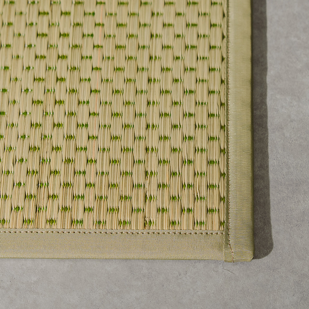 A folded three-fold green igusa tatami mat on a wood floor.