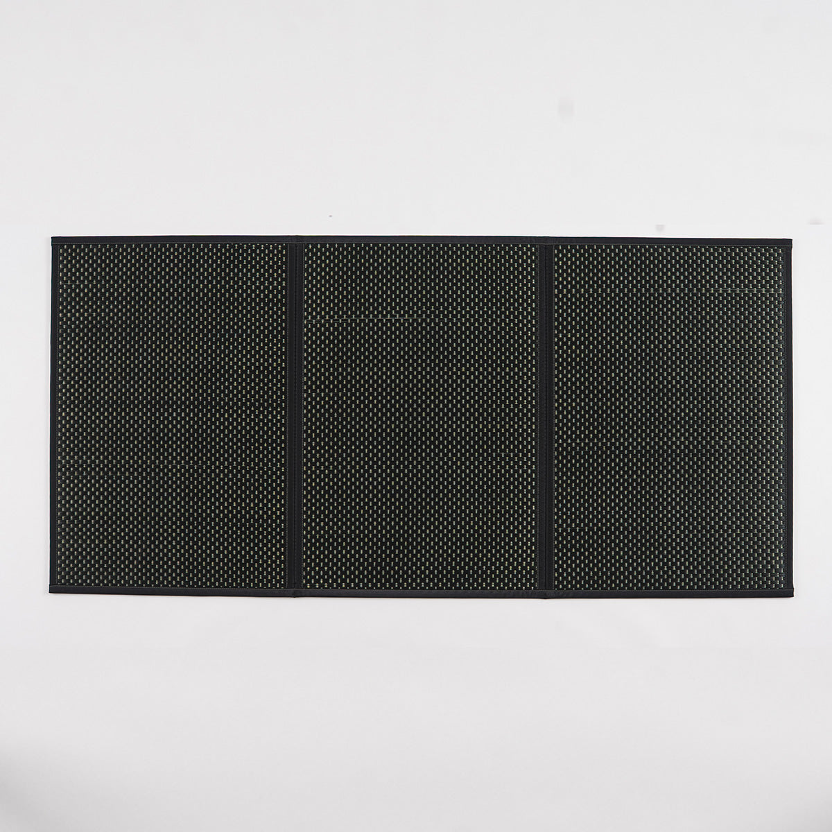 A folded three-fold black igusa tatami mat on a wood floor.